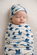 Newborn baby in Gus goose print stretchy swaddle and matching beanie, TENCEL Modal swaddle set